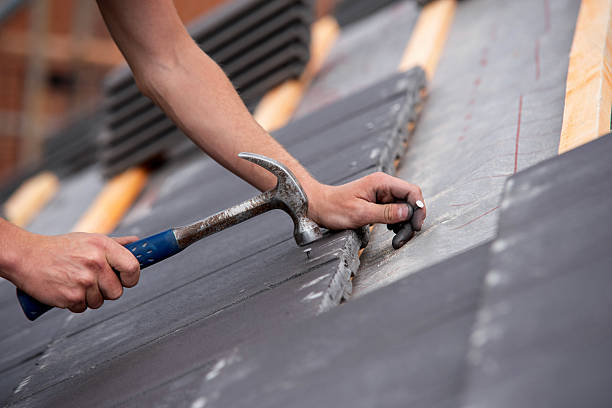 SwiftFix | Emergency Roof Repair in Edinburgh Close-up of skilled builder hands carefully placing roofing tiles on sloped surface of building and using hammer to ensure proper alignment